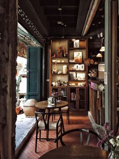 a room with tables, chairs and shelves full of books on the wall behind them