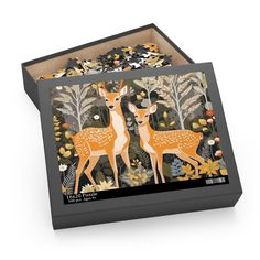 two deers are standing in the woods surrounded by leaves and flowers on a black box