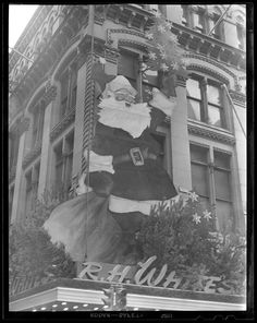 an old black and white photo of santa claus on the side of a tall building