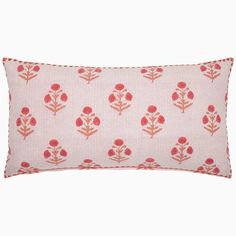 a pink and white pillow with red flowers on the front, sitting against a white background