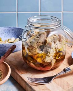 a glass jar filled with food sitting on top of a wooden cutting board