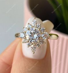 a woman's hand with a ring on it and a flower shaped diamond in the middle