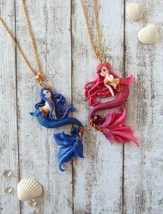 three necklaces with different designs on them sitting on top of a white wooden table