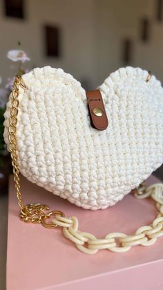 a white crocheted purse sitting on top of a pink table