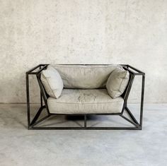 a chair sitting on top of a cement floor next to a wall with a white pillow