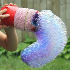 a child holding up a rainbow bubble snake toy in the air with text overlay reading rainbow bubble snakes