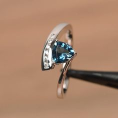 It is a London blue topaz ring. The main stone is 6mm*6mm trillion cut, weight about 1.02 carats. The basic metal is sterling silver and plated with rhodium. To change the metal to a solid gold (white/rose) or platinum is also available, please ask for a quotation if you want. You can also go to my shop Home for more elegant rings: https://www.etsy.com/shop/godjewelry?ref=hdr_shop_menu More London blue topaz rings: https://www.etsy.com/shop/godjewelry?search_query=London+blue+topaz Customization Luxury Diamond Cut Topaz Promise Ring, Luxury Topaz Promise Ring With Tension Setting, Luxury Brilliant Cut Topaz Ring For Promise, Luxury Fine Jewelry Topaz Proposal Ring, Luxury Fine Jewelry Topaz Ring For Proposal, Luxury Solitaire Topaz Ring In Sterling Silver, Luxury Platinum Topaz Ring For Gift, Luxury Elegant Trillion Cut Topaz Ring, Luxury Trillion Cut Topaz Ring For Formal Events