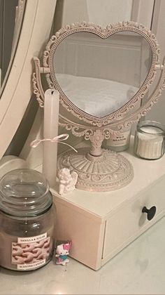 a vanity with a mirror, candle and other items on it