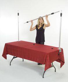 a woman standing behind a red table with two metal bars on it's head