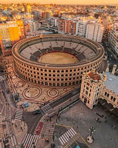 an aerial view of a large circular building in the middle of a city with lots of tall buildings