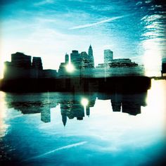 a city skyline is reflected in the water