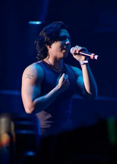 a man with long hair and tattoos on his arm singing into a microphone