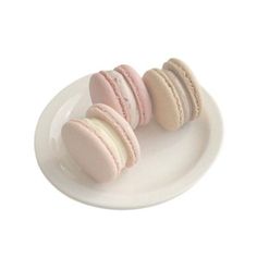 three macaroons are on a white plate and one has pink frosted icing