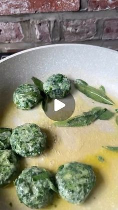 a white bowl filled with broccoli covered in cheese and sauce next to a brick wall