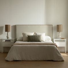 a bedroom with a bed, nightstands and two lamps on either side of the bed