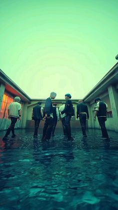 four men in suits and ties standing on the roof of a building with water surrounding them