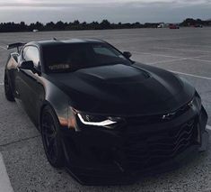 a black chevrolet camaro is parked in a parking lot with no one around it