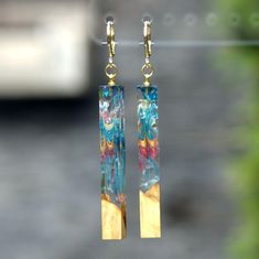 a pair of gold and blue earrings hanging from a hook - on earwires