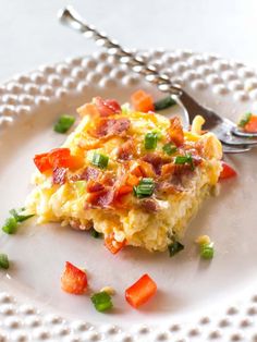 a white plate topped with an omelet covered in bacon and veggies