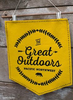 a yellow sign hanging on the side of a wooden building that says, the great outdoors pacific northwest