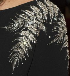 the back of a woman's black dress with silver sequins on it