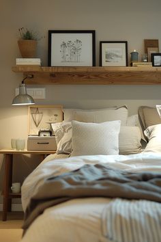 a bed with pillows, blankets and pictures on the wall above it in a bedroom