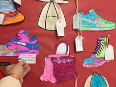 handmade paper shoes are hanging on a red wall with price tags attached to them