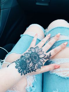 a woman's hand with sunflower tattoo on it sitting in the back seat of a car