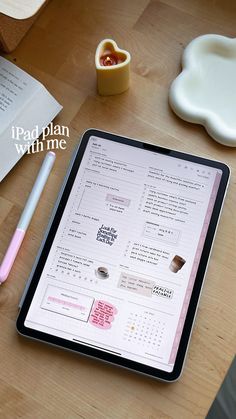 a tablet computer sitting on top of a wooden table next to a cup and pen