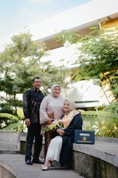 two men and a woman are posing for a photo on the steps in front of a building