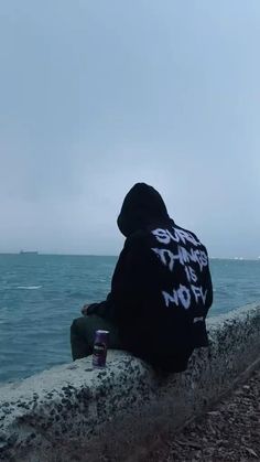 a person sitting on a ledge looking out at the ocean