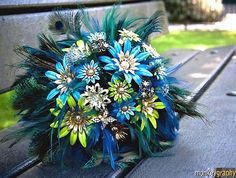 a bouquet of blue flowers and feathers on a bench