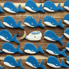 blue whale cookies are arranged in rows on a wooden board with the words painted pastry