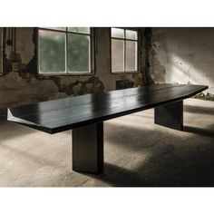 a long black table sitting in an empty room next to two windows with no one on it