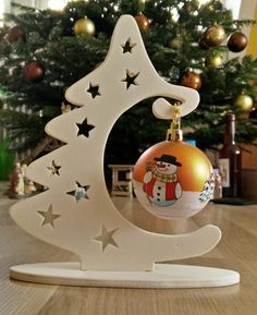 a christmas tree ornament with a snowman on top and stars around it