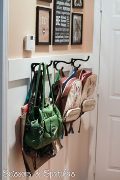 several purses are hanging on the hooks in this entryway area, which is decorated with chalkboard and framed pictures