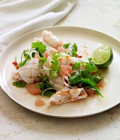 a white plate topped with shrimp and garnish next to a slice of lime