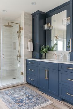 a bathroom with blue cabinetry and gold hardware on the vanity, along with a rug