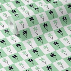 a green and white checkered wallpaper with black flowers on the top of it