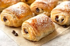 croissants with raisins and powdered sugar sit on parchment paper