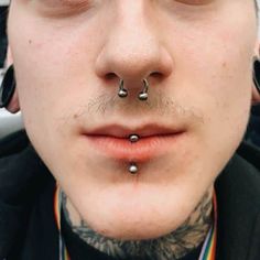 a man with piercings on his nose looks at the camera