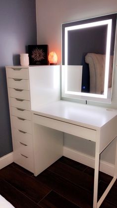 a white desk with a lighted mirror and drawers