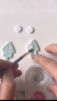 someone is painting some white flowers on a piece of paper with acrylic paint