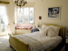 a bedroom with a bed, chandelier and window in the corner next to it