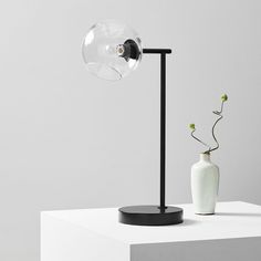 a white vase sitting on top of a table next to a black and white lamp