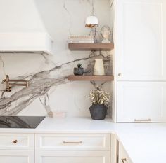 a kitchen with white cabinets and marble counter tops, gold faucet pulls on the cabinet doors