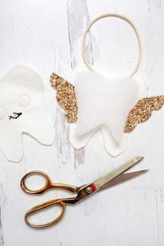 scissors are laying next to the cut out tooth and angel decorations on a white wooden surface