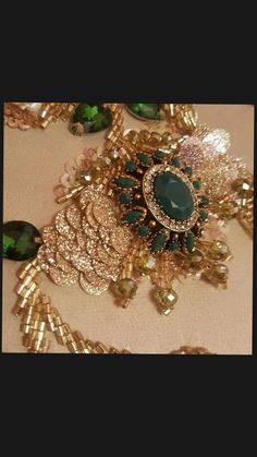 an assortment of green and gold brooches on a tablecloth with other items