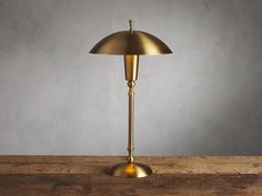 an antique brass table lamp on a wooden surface with a gray wall in the background