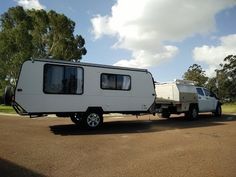 a white truck towing a camper on the road